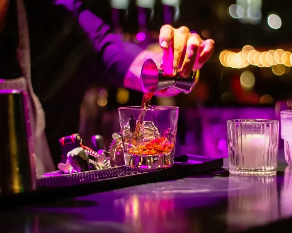 Bartender pouring a cocktail over clear ice